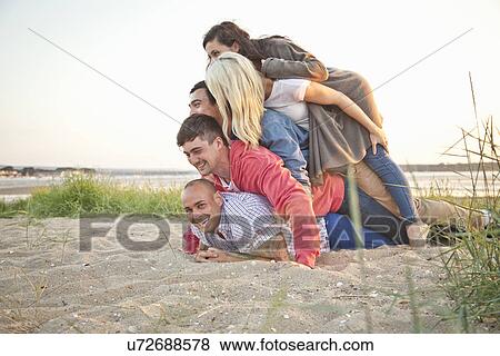 Group of friends making human pile on beach View Large Photo Image Stock Photo - Group of friends making human pile on beach. Fotosearch