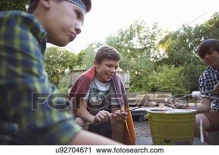 Group of young boys toasting marshmallows over bucket barbecue View Large Photo Image Stock Image - Group of young boys toasting marshmallows over bucket barbecue. Fotosearch