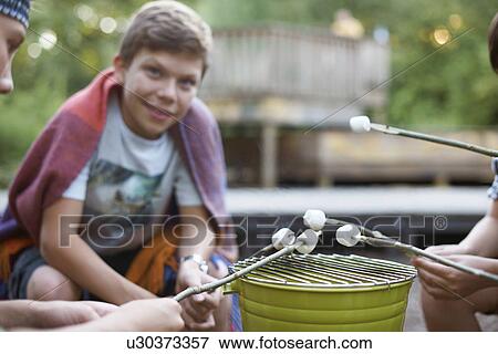 Group of young boys toasting marshmallows over bucket barbecue View Large Photo Image Stock Photo - Group of young boys toasting marshmallows over bucket barbecue. Fotosearch