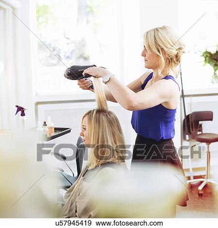 Hairdresser drying customer's hair with hairdryer View Large Photo Image Stock Photo - Hairdresser drying customer's hair with hairdryer. Fotosearch
