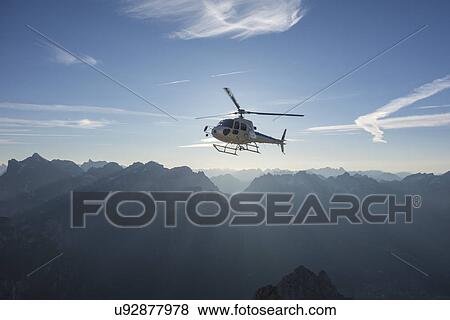Stock Photo - Helicopter on scenic flight at sunrise, Alleghe, Dolomites, Italy. Fotosearch