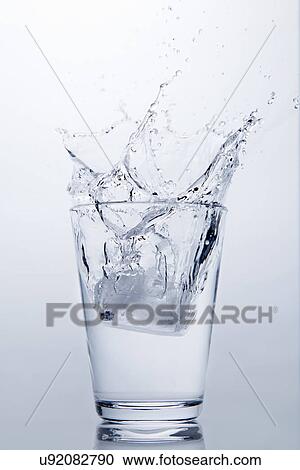 Ice cube splashing into glass of clear water View Large Photo Image Stock Image - Ice cube splashing into glass of clear water. Fotosearch