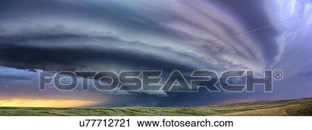 Stock Image - Large arcus cloud sweeps around the updraft of anticyclonic supercell with sunset colors projected on the cloud, Deer Trail, Colorado, USA. Fotosearch