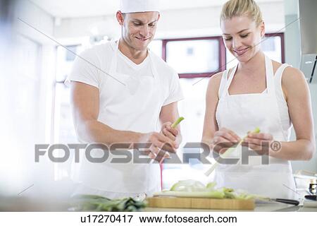 Stock Photo - Male and female chefs peeling leeks in commercial kitchen. Fotosearch