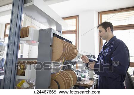 Male electrician pulling power cable from cable drum in workshop View Large Photo Image Stock Photography - Male electrician pulling power cable from cable drum in workshop. Fotosearch