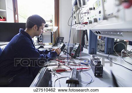 Stock Image - Male electrician repairing electronic equipment in workshop. Fotosearch