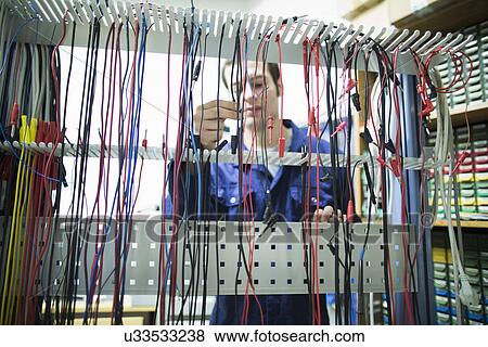 Stock Photo - Male electrician selecting power cable in workshop. Fotosearch
