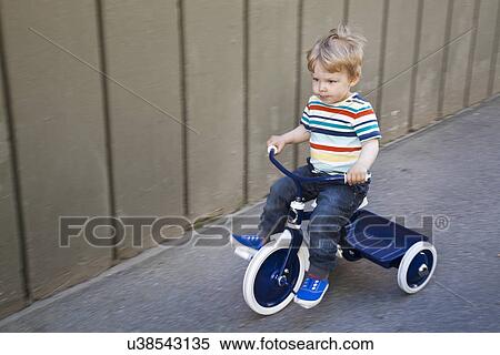 Male toddler playing on tricycle in garden View Large Photo Image Stock Photography - Male toddler playing on tricycle in garden. Fotosearch