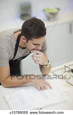 Stock Photo - Man reading recipe in cookbook. Fotosearch