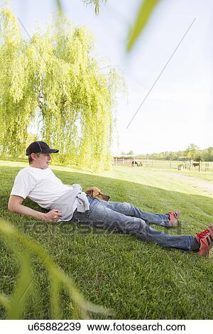Man relaxing on grass with dog View Large Photo Image Stock Photo - Man relaxing on grass with dog. Fotosearch