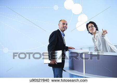 Stock Image - Mature adult man asking receptionist for directions. Fotosearch