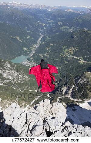 Stock Photo - Mature man BASE jumping from mountain, Alleghe, Dolomites, Italy. Fotosearch