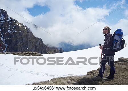 Stock Photograph - Mature man standing in snow, Bucegi Mountains, Transylvania, Romania. Fotosearch