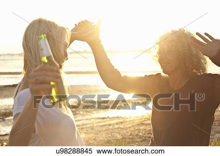Stock Photography - Mature mother and daughter dancing on Bournemouth beach, Dorset, UK. Fotosearch