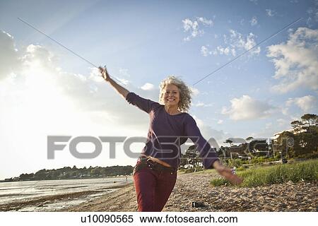 Stock Photography - Mature woman enjoying beach. Fotosearch