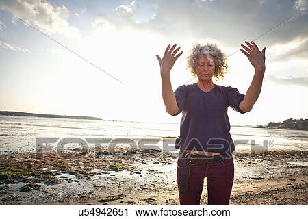 Stock Image - Mature woman exercising on beach. Fotosearch