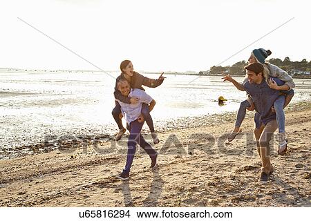 Men giving piggyback ride to women on beach View Large Photo Image Picture - Men giving piggyback ride to women on beach. Fotosearch