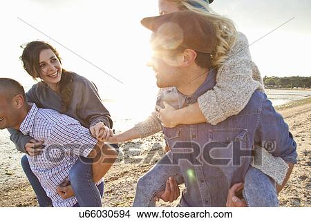 Men giving piggyback ride to women on beach View Large Photo Image Picture - Men giving piggyback ride to women on beach. Fotosearch