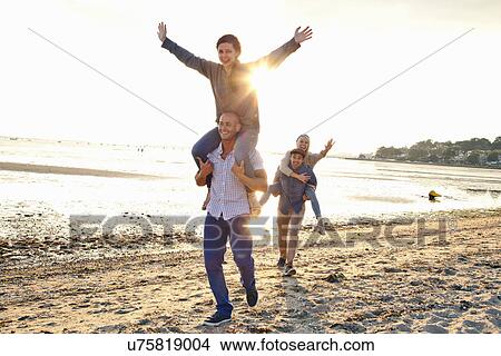Men giving piggyback ride to women on beach View Large Photo Image Picture - Men giving piggyback ride to women on beach. Fotosearch