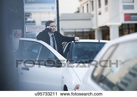 Mid adult businessman chatting on smartphone in city traffic jam View Large Photo Image Stock Image - Mid adult businessman chatting on smartphone in city traffic jam. Fotosearch