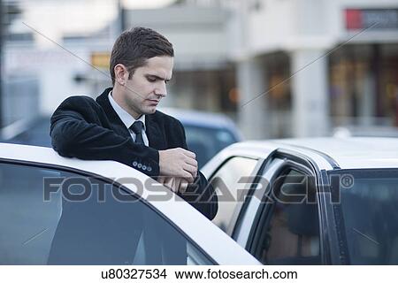 Mid adult businessman looking at watch in city traffic jam View Large Photo Image Picture - Mid adult businessman looking at watch in city traffic jam. Fotosearch