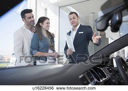 Mid adult couple and salesman chatting in car dealership View Large Photo Image Stock Photograph - Mid adult couple and salesman chatting in car dealership. Fotosearch