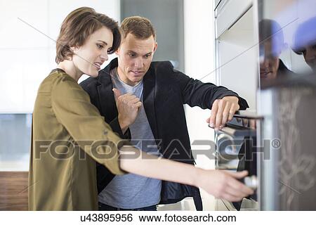 Mid adult couple inspecting oven in kitchen showroom View Large Photo Image Stock Photograph - Mid adult couple inspecting oven in kitchen showroom. Fotosearch