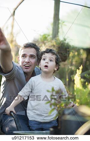 Mid adult man and son looking surprised in garden View Large Photo Image Stock Image - Mid adult man and son looking surprised in garden. Fotosearch