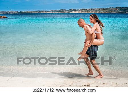 Mid adult man giving girlfriend piggy back on beach, La Maddalena, Sardinia, Italy View Large Photo Image Stock Image - Mid adult man giving girlfriend piggy back on beach, La Maddalena, Sardinia, Italy. Fotosearch