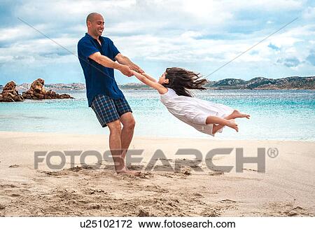 Mid adult man swinging daughter on beach, La Maddalena, Sardinia, Italy View Large Photo Image Stock Image - Mid adult man swinging daughter on beach, La Maddalena, Sardinia, Italy. Fotosearch