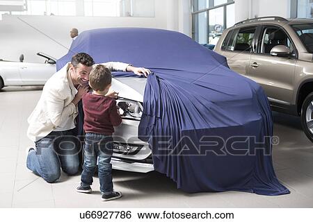 Mid adult man uncovering new car for son in car dealership View Large Photo Image Stock Photograph - Mid adult man uncovering new car for son in car dealership. Fotosearch