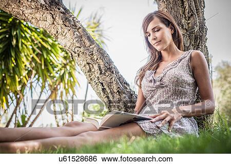 Mid adult woman reading book under palm tree in holiday home garden, Capoterra, Sardinia, Italy View Large Photo Image Stock Photograph - Mid adult woman reading book under palm tree in holiday home garden, Capoterra, Sardinia, Italy. Fotosearch