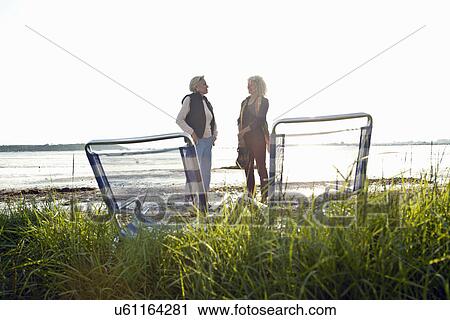 Stock Image - Mother and daughter chatting on beach. Fotosearch
