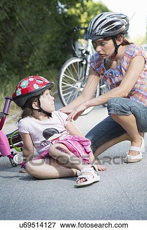 Mother caring for daughter fallen off bicycle View Large Photo Image Stock Photo - Mother caring for daughter fallen off bicycle. Fotosearch