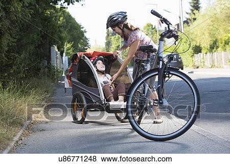 Mother with daughter in bicycle trailer View Large Photo Image Stock Photo - Mother with daughter in bicycle trailer. Fotosearch