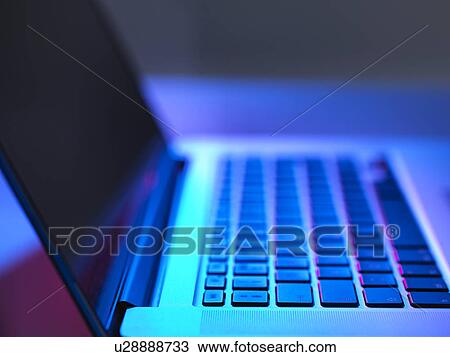 Stock Image - Open laptop on desk at night. Fotosearch