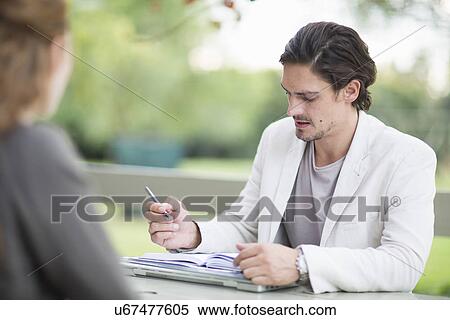 Over the shoulder view of businessman in garden making notes in diary View Large Photo Image Stock Photography - Over the shoulder view of businessman in garden making notes in diary. Fotosearch