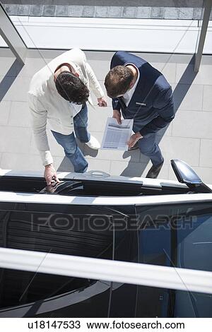 Overhead view of salesman and customer looking at new car in car dealership View Large Photo Image Stock Image - Overhead view of salesman and customer looking at new car in car dealership. Fotosearch
