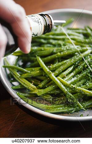 Stock Photo - Person pouring sauce on green beans. Fotosearch