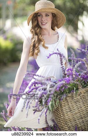 Portrait of beautiful young woman in garden with basket of purple flowers View Large Photo Image Picture - Portrait of beautiful young woman in garden with basket of purple flowers. Fotosearch
