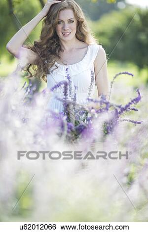 Portrait of beautiful young woman in meadow of purple flowers View Large Photo Image Stock Photograph - Portrait of beautiful young woman in meadow of purple flowers. Fotosearch