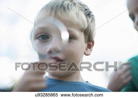 Portrait of boy holding magnifying glass in front of eye View Large Photo Image Stock Photography - Portrait of boy holding magnifying glass in front of eye. Fotosearch