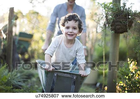 Portrait of boy riding in wheelbarrow on allotment View Large Photo Image Stock Photo - Portrait of boy riding in wheelbarrow on allotment. Fotosearch