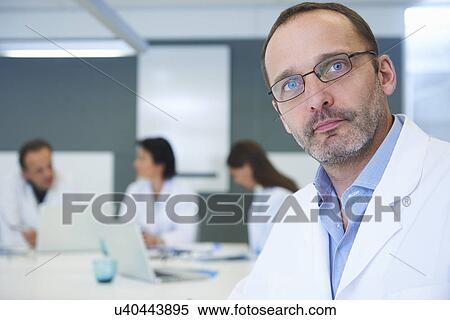 Portrait of male doctor, colleagues having discussion behind View Large Photo Image Stock Photography - Portrait of male doctor, colleagues having discussion behind. Fotosearch