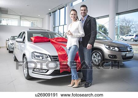 Portrait of mid adult couple and new car with red bow in car dealership View Large Photo Image Stock Image - Portrait of mid adult couple and new car with red bow in car dealership. Fotosearch