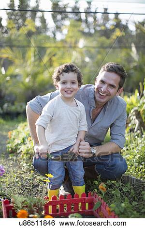 Portrait of mid adult man and son gardening in allotment View Large Photo Image Stock Photograph - Portrait of mid adult man and son gardening in allotment. Fotosearch