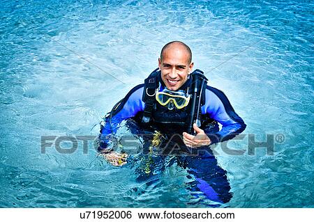 Stock Photograph - Portrait of mid adult man scuba diving in sea, La Maddalena, Sardinia, Italy. Fotosearch
