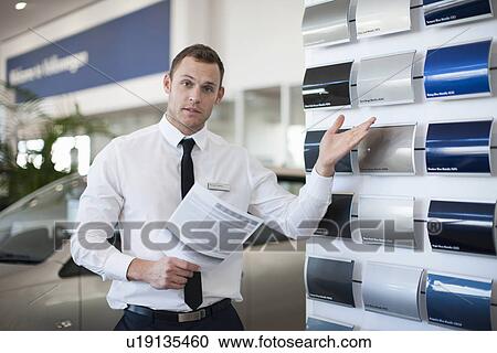 Portrait of salesman gesturing to color swatches in car dealership View Large Photo Image Stock Image - Portrait of salesman gesturing to color swatches in car dealership. Fotosearch