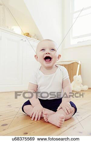 Stock Photo - Portrait of smiling baby boy sitting on floor. Fotosearch