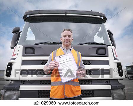 Stock Image - Portrait of trainee truck driver holding pass certificate. Fotosearch
